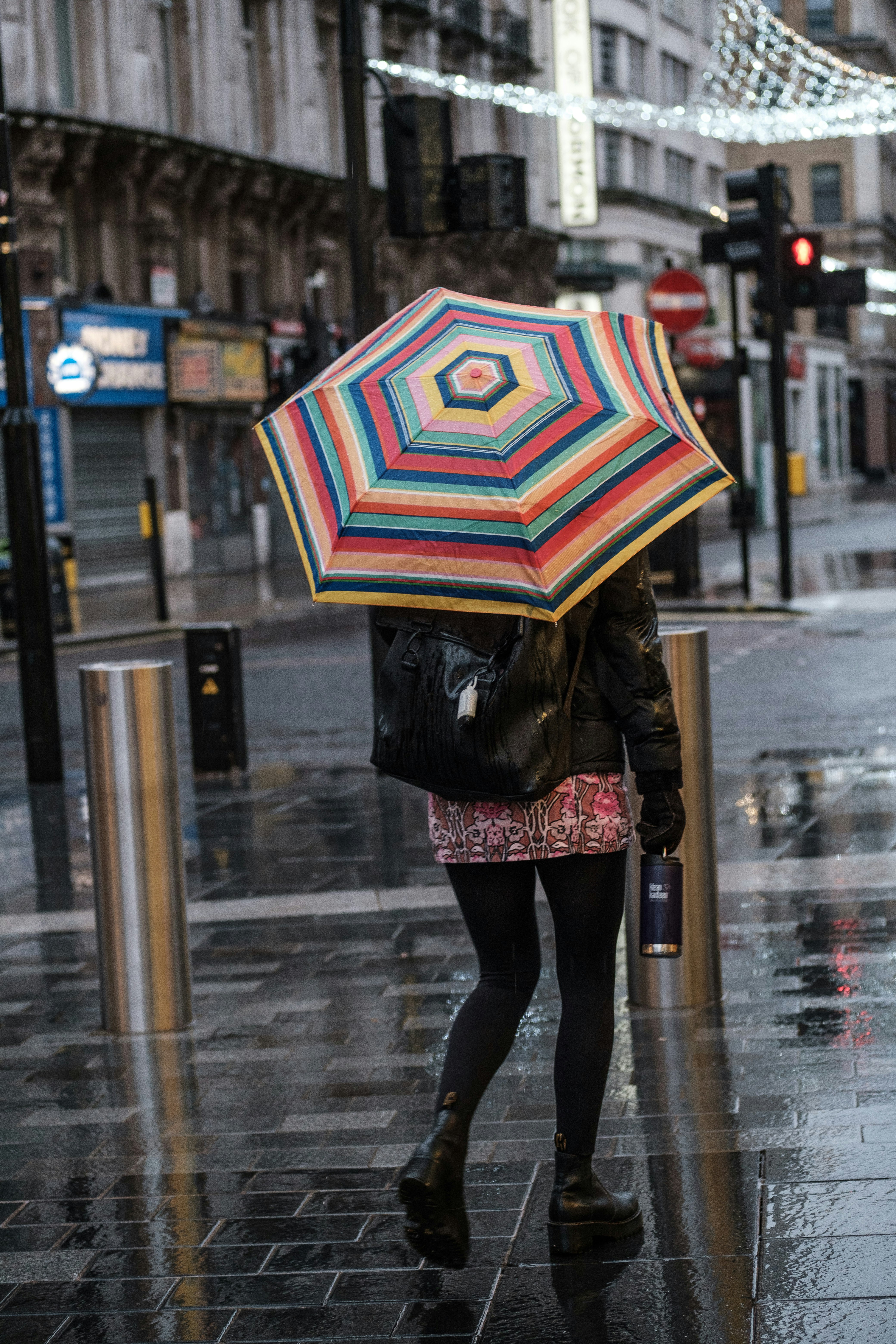 person in black jacket holding umbrella walking on sidewalk during daytime